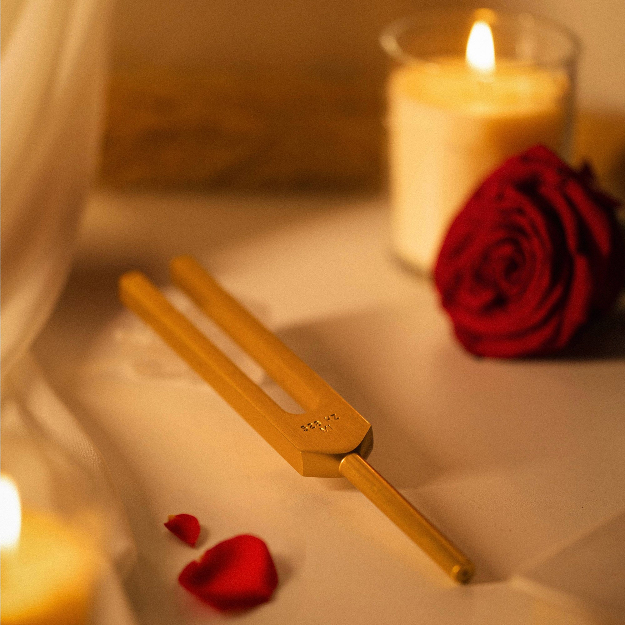 528Hz Gold Colored Tuning Fork in a spa-like environment with roses and candles